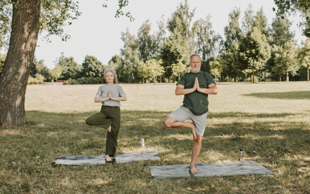 Pareja de más de 60 años haciendo ejercicios de equilibrio en un parque