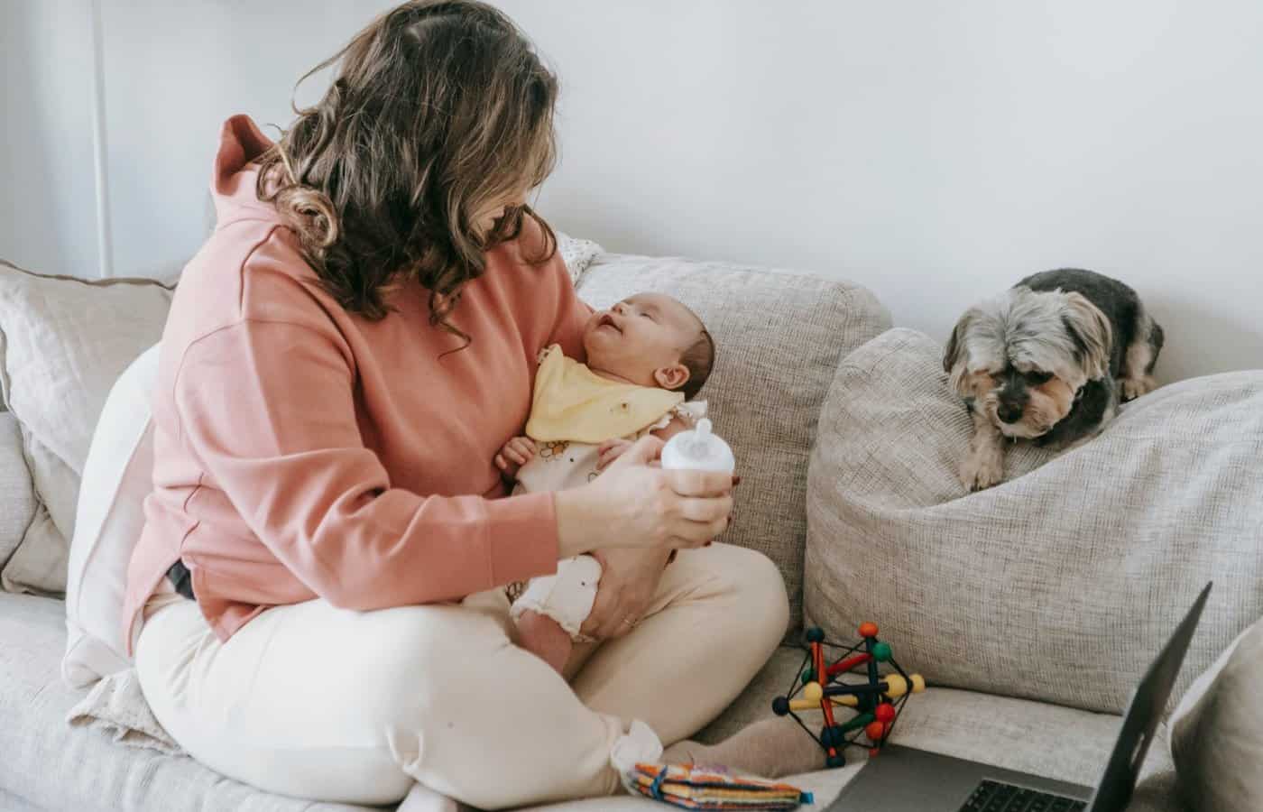 Mère assise sur le canapé donnant le biberon à son bébé