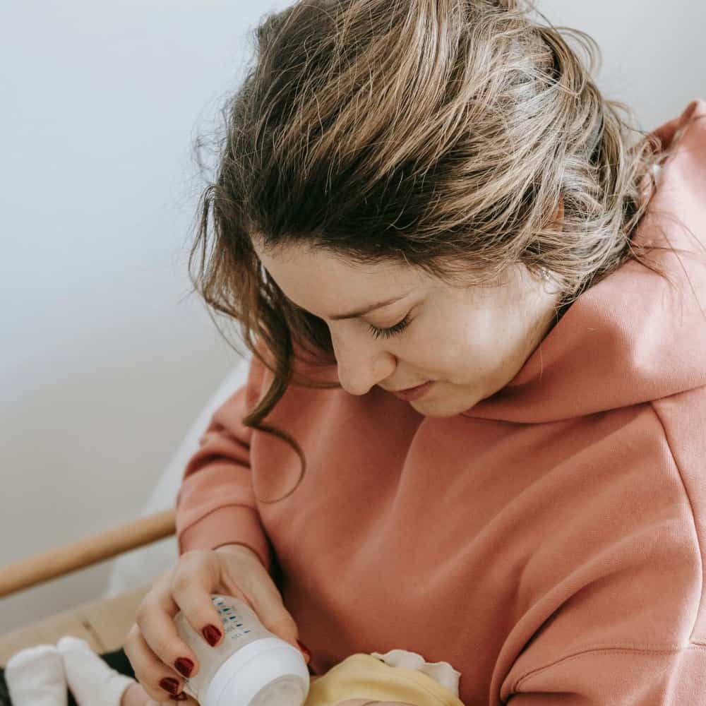 Mère voûtée au-dessus de son bébé en lui donnant le biberon