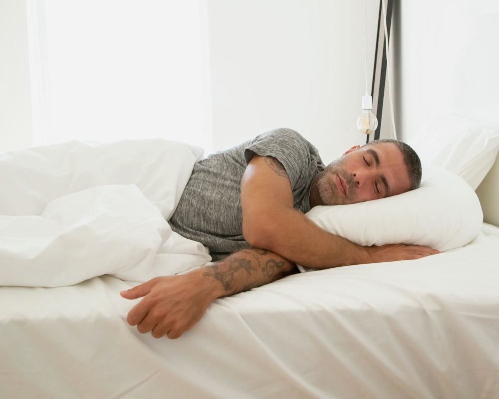 Hombre durmiendo de lado con el cuello alineado sobre la almohada