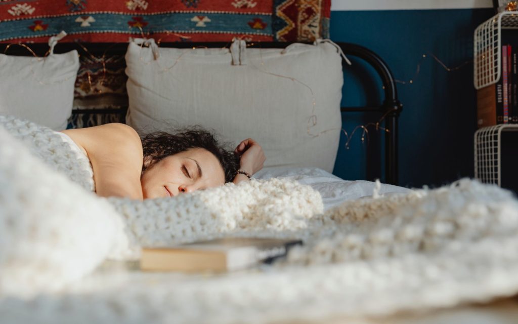 Mujer durmiendo de lado en una cama, con la cabeza apoyada en la almohada
