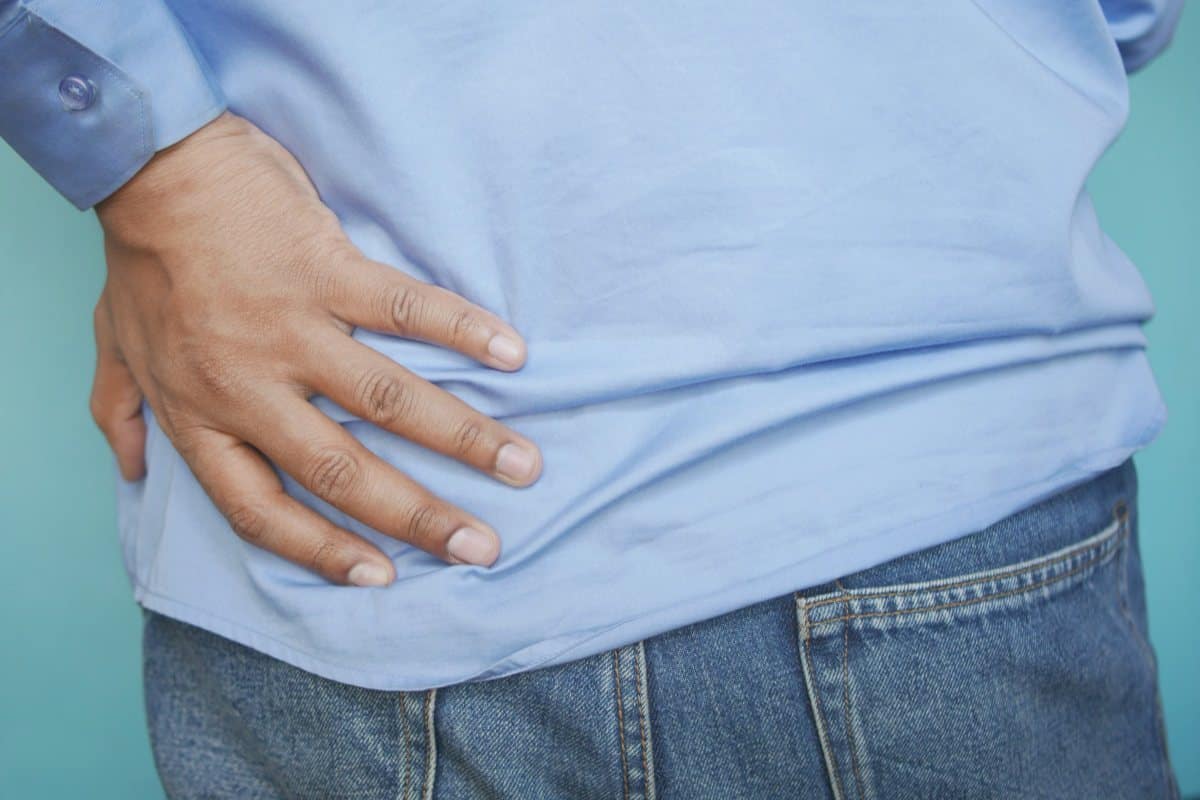 Persona que se lleva la mano a la cadera y la zona lumbar