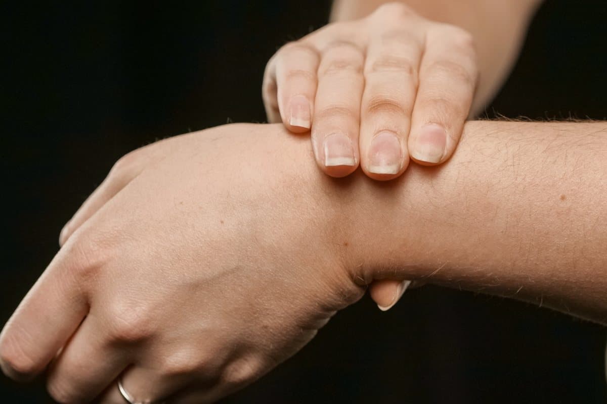 Persona que se sujeta la muñeca con la otra mano