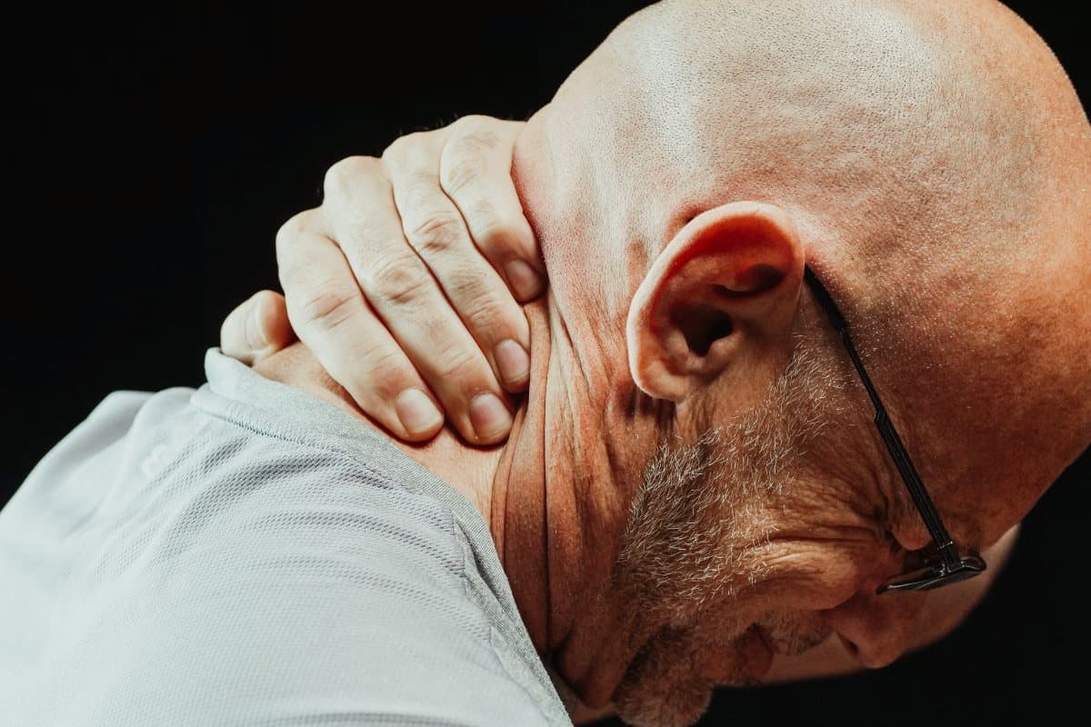 Hombre mayor que se sujeta la nuca con la mano